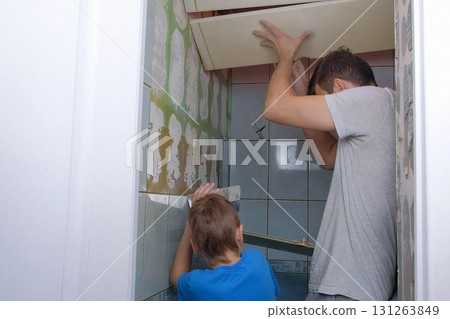 Ceiling covering falls on dad and son while they are doing home repairs. Ceiling covering falls on dad and son while they are doing home repairs. 131263849