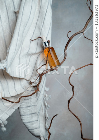 Bottle with vitamin serum and white cotton towel on a willow branch, 131263973