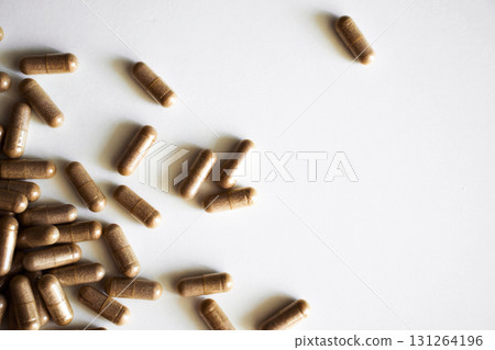 Brown herbal capsules scattered on white background with natural soft light Brown herbal capsules scattered on white background with natural soft light 131264196