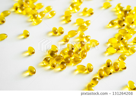 Shiny golden capsules lying on white surface with soft reflections of light 131264208