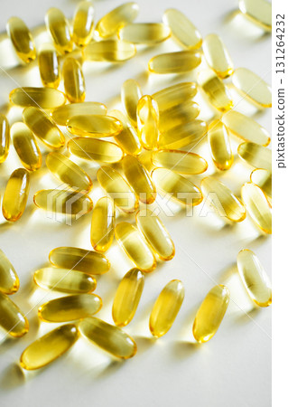 Heap of golden omega 3 capsules close-up on white background with bright light Heap of golden omega 3 capsules close-up on white background with bright light 131264232