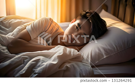 Peaceful person sleeping comfortably in a cozy bed, illuminated by soft morning light 131264291