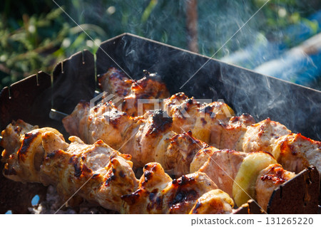 Grilled kebab cooking on metal skewer. Roasted meat cooked at barbecue.Traditional eastern dish, shish kebab. Grill on charcoal and flame, picnic, street food 131265220