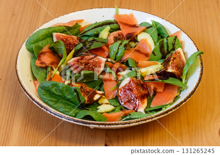 Healthy salad with smoked salmon, spinach, avocado and fig on wooden table Healthy salad with smoked salmon, spinach, avocado and fig on wooden table 131265245