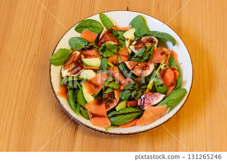 Healthy salad with smoked salmon, spinach, avocado and fig on wooden table 131265246