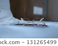 Glasses on bed Stylish lamp, book and glasses on bedside table indoors. Bedroom interior elements 131265499
