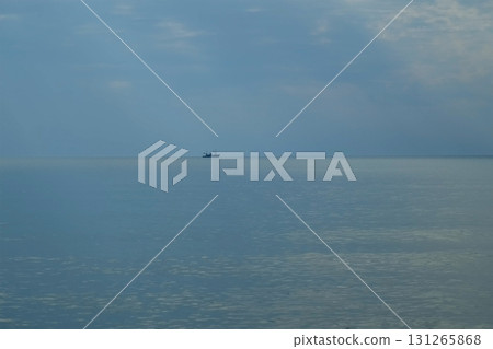 Lonely fishing boat sailing on calm sea under cloudy sky in evening. 131265868