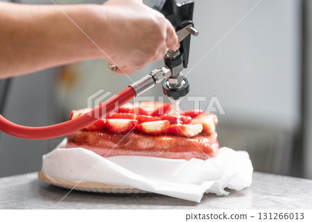 A pastry chef applying icing to a cake with a professional icing gun. The chef hands are clearly A pastry chef applying icing to a cake with a professional icing gun. The chef hands are clearly 131266013