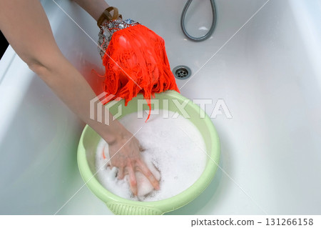 Woman is washing dance dress in basin in soapy water, laundry by hands. 131266158
