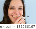 Young woman with yellow bad teeth smoking a cigarrete smiling looking at camera. 131266167