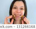 Young woman with yellow bad teeth keeping candy in hands and smiling. 131266168