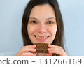 Young woman with yellow bad teeth keeping candy in hands, smelling and smiling. 131266169
