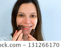 Young woman with yellow bad teeth keeping candys in hands and smiling. 131266170