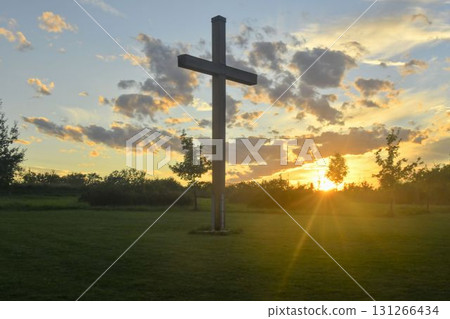 A large Christian cross in the scenery of a landscape. A Christian cross lighted by the setting sun. The concept of religion and Christianity. 131266434