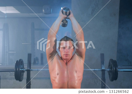 Man bodybuilder training dumbbell triceps extension exercise lifting overhead. Man bodybuilder training dumbbell triceps extension exercise lifting overhead. 131266562