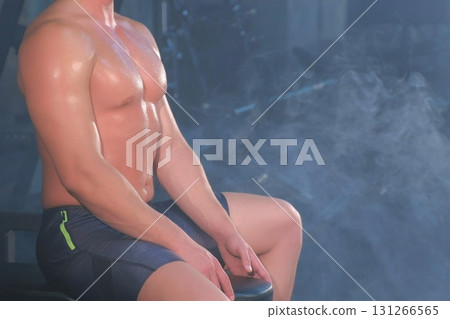 Professional muscular body of athletic man bodybuilder sitting on bench in gym. Professional muscular body of athletic man bodybuilder sitting on bench in gym. 131266565