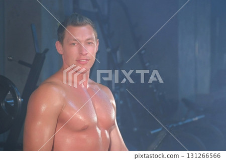 Portrait professional muscular athletic man bodybuilder sitting on bench in gym. Portrait professional muscular athletic man bodybuilder sitting on bench in gym. 131266566