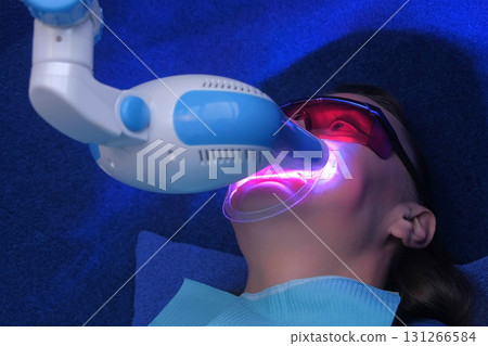 LED whitening beauty cosmetic procedure for woman's teeth in dentistry studio. LED whitening beauty cosmetic procedure for woman's teeth in dentistry studio. 131266584