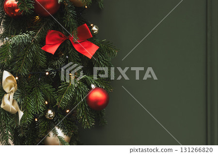Christmas tree branches with red balls and a golden bow on a green background 131266820