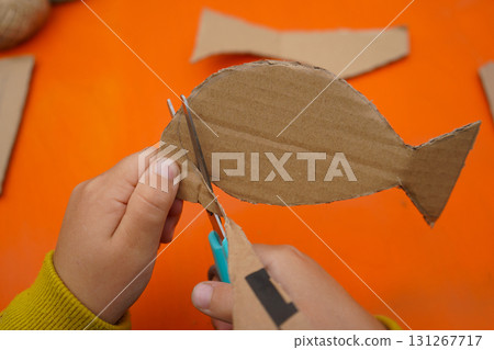 Craft a fish out of cardboard, thread, and paint, following step-by-step directions, with an orange background. Craft a fish out of cardboard, thread, and paint, following step-by-step directions, with an orange background. 131267717
