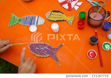 Assemble a fish sculpture from cardboard, thread, and paint, with detailed steps, set against an orange background. Assemble a fish sculpture from cardboard, thread, and paint, with detailed steps, set against an orange background. 131267719