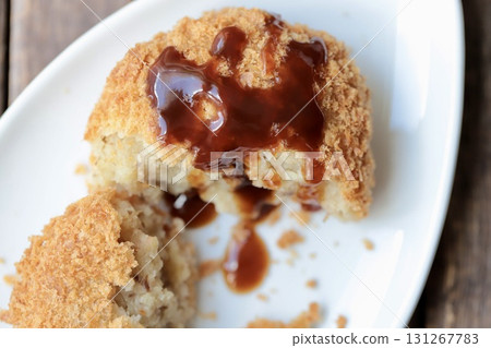 A fluffy Hokkaido potato croquette cut in half and topped with sauce 131267783