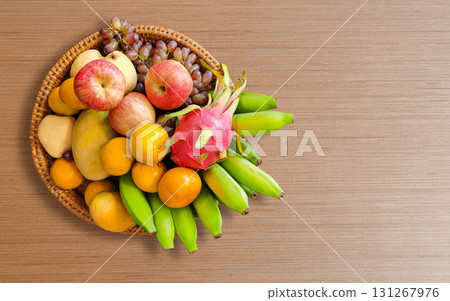 Various fruits in a wooden tray placed on a wooden table. 131267976