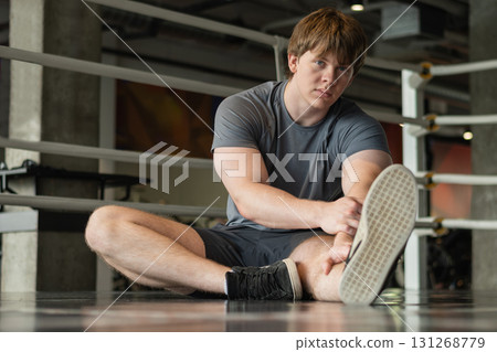 Athlete and young sporty man doing stretching legs at gym before workout. Training, wellness and athlete man workout. Preparation for exercise at health club. Athlete and young sporty man doing stretching legs at gym before workout. Training, wellness and athlete man workout. Preparation for exercise at health club. 131268779