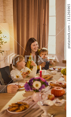 Young mother with children laughing at festive family dinner table Young mother with children laughing at festive family dinner table 131268965