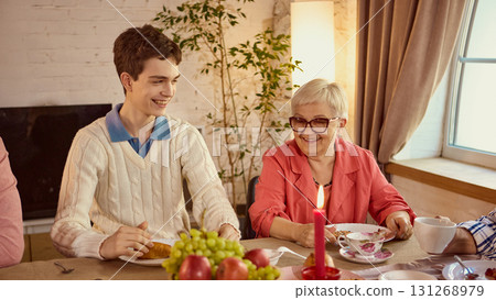 Smiling teenager with grandmother at family dinner table with warm candlelight Smiling teenager with grandmother at family dinner table with warm candlelight 131268979