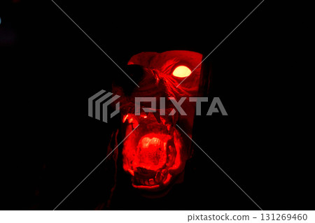 A snarling monster dog head glows bright red in the dark. Fangs, open mouth, and fiery eyes create a scary Halloween display. A snarling monster dog head glows bright red in the dark. Fangs, open mouth, and fiery eyes create a scary Halloween display. 131269460