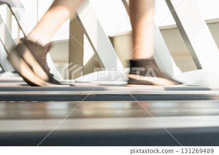 Mans legs running on treadmill in modern gym. Motion blur legs show speed and intensity. Workout session. Abstract sport background. Side view. Close up. 131269489