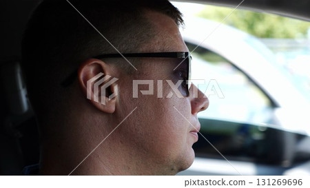 Profile of confident man driving a motor car at town. Male face of male driver in sunglasses looking concentrated to urban road while riding automobile. Slow motion Profile of confident man driving a motor car at town. Male face of male driver in sunglasses looking concentrated to urban road while riding automobile. Slow motion 131269696