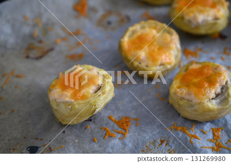 Delicious stuffed artichoke hearts topped with melted cheese on a rustic baking tray Delicious stuffed artichoke hearts topped with melted cheese on a rustic baking tray 131269980