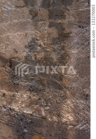 Ancient carvings tell a story of forgotten cultures on a weathered rock face in an arid landscape 131270003