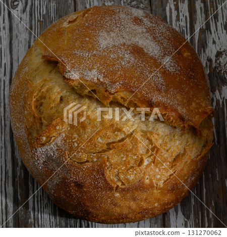 Freshly baked rustic bread resting on a wooden surface in warm lighting during a cozy afternoon Freshly baked rustic bread resting on a wooden surface in warm lighting during a cozy afternoon 131270062