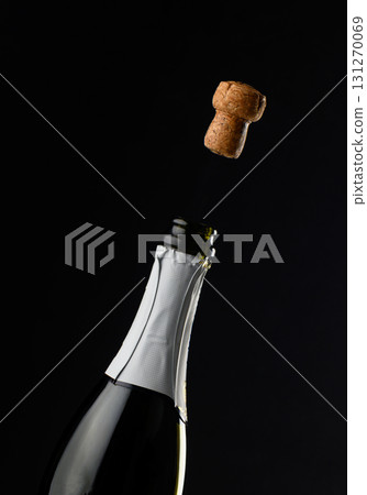 Celebration moment as cork pops from bottle of champagne in dramatic low light Celebration moment as cork pops from bottle of champagne in dramatic low light 131270069
