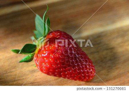 Freshly picked strawberry resting on a wooden surface captured in soft natural Freshly picked strawberry resting on a wooden surface captured in soft natural 131270081