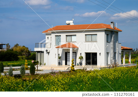 Charming modern house surrounded by blooming flowers in a sunny countryside landscape Charming modern house surrounded by blooming flowers in a sunny countryside landscape 131270161