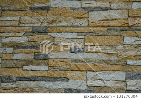 Natural stone wall with a blend of earthy tones and textures creating a rustic aesthetic 131270304