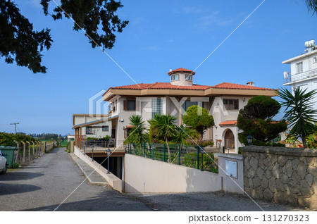 Elegant residential villa with lush greenery in a serene suburban setting near the coast on a clear day 131270323