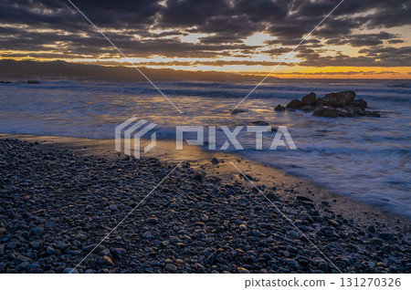 Beautiful sunset over rocky beach with waves gently lapping at the shore Beautiful sunset over rocky beach with waves gently lapping at the shore 131270326