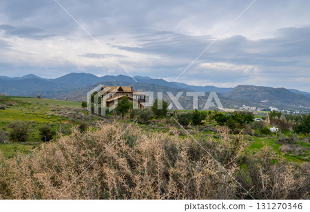 Serene stone house nestled among rolling hills under a moody sky at dusk 131270346