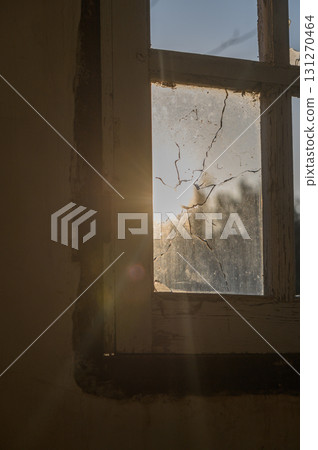 Sunlight filtering through a cracked window in an abandoned building at dusk Sunlight filtering through a cracked window in an abandoned building at dusk 131270464