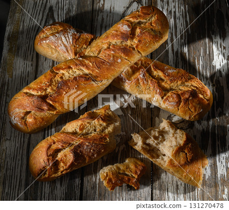 Freshly baked artisan bread arranged beautifully on rustic wooden table in soft 131270478