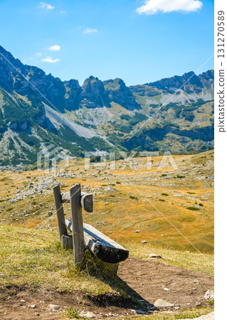 Wooden bench photographed from side with panoramic view of mountains and hills in Sedlo, Durmitor National Park, Montenegro. Perfect for autumn travel, outdoor lifestyle, and scenic landscape concepts 131270589