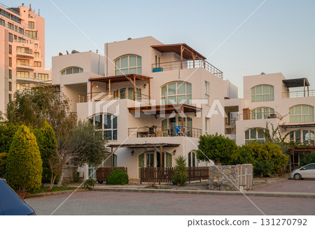 Modern architecture shines under the soft glow of sunset in a coastal community filled with vibrant greenery 131270792