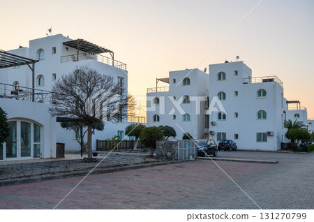 Whitewashed buildings gleam under the soft golden glow of sunset in a serene neighborhood Whitewashed buildings gleam under the soft golden glow of sunset in a serene neighborhood 131270799