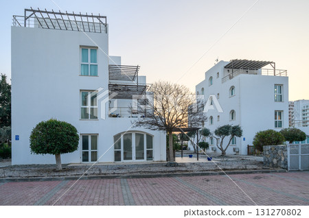 Modern white buildings stand quietly in the soft light of dawn by a serene path with minimal landscaping 131270802