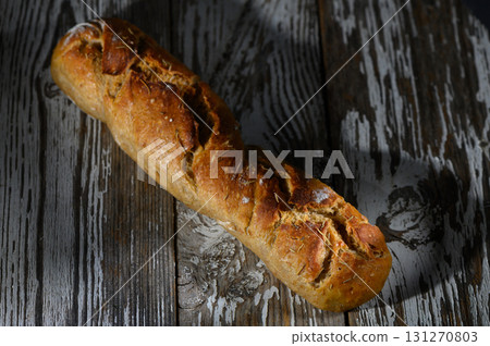 Freshly baked artisan loaf resting on rustic wooden surface during the golden hour glow Freshly baked artisan loaf resting on rustic wooden surface during the golden hour glow 131270803
